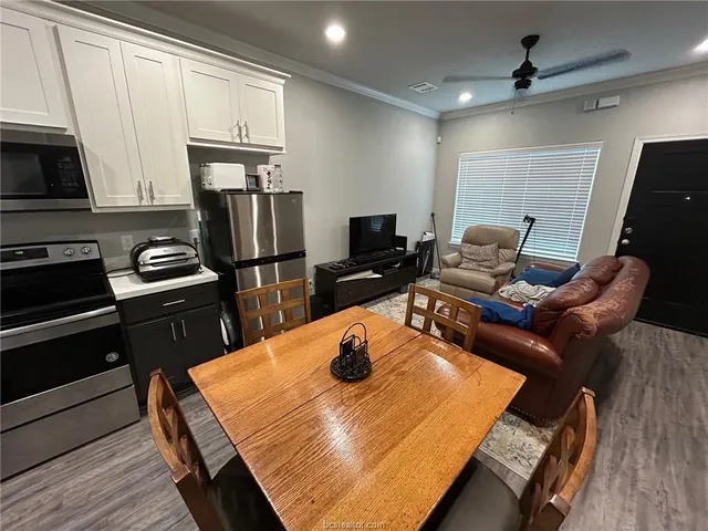 a kitchen with stainless steel appliances kitchen island granite countertop a refrigerator stove top oven dining table and chairs