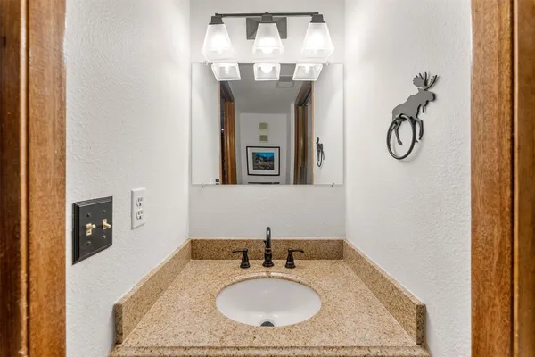 a bathroom with a granite countertop sink a mirror and a shower