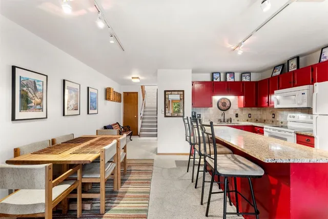 a kitchen with stainless steel appliances kitchen island granite countertop a dining table chairs and white cabinets