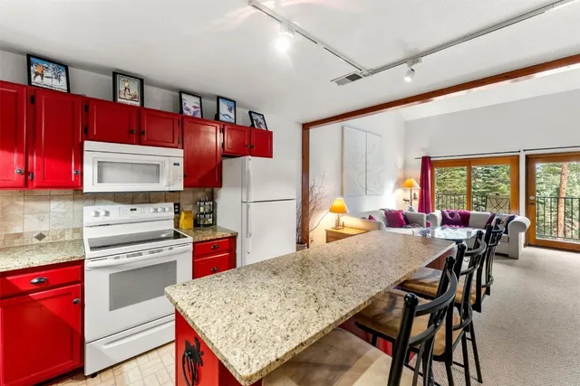 a kitchen with stainless steel appliances granite countertop a stove refrigerator sink dining table and chairs