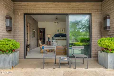 a patio with table and chairs and potted plants