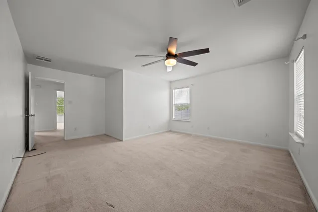 an empty room with windows and chandelier fan