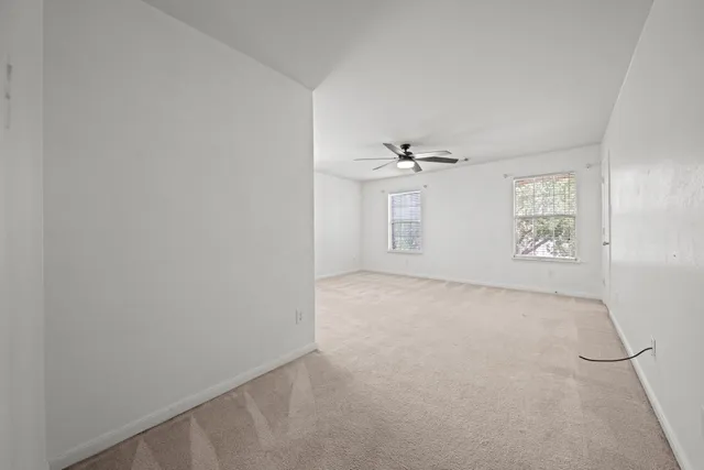 an empty room with windows and fan