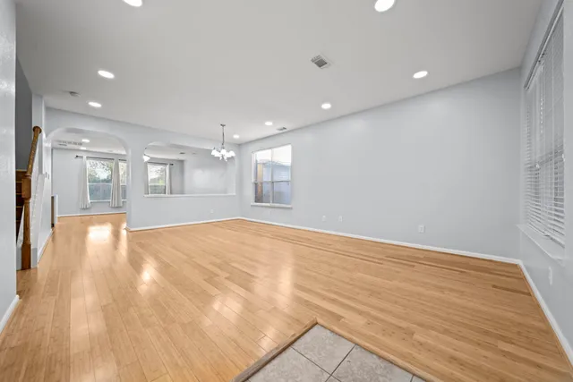 a view of an empty room with wooden floor and a kitchen