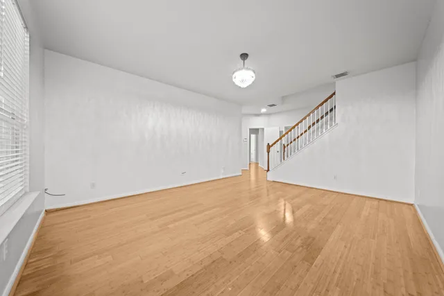 a view of an empty room with wooden floor and stairs