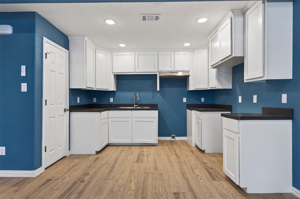 603 East Willingham Street Cleburne, TX 76031 - Photo 10 of 25 a kitchen with granite countertop white cabinets and white appliances