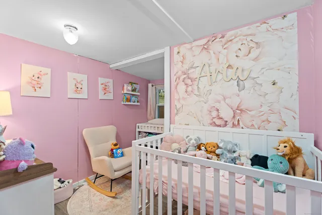 a living room with a baby crib with couch and a chair