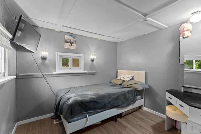 a bedroom with a bed and a potted plant on the dresser
