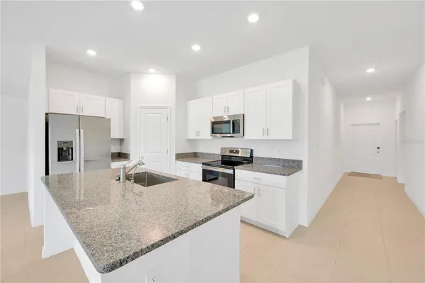 a kitchen with stainless steel appliances granite countertop a sink a stove and refrigerator