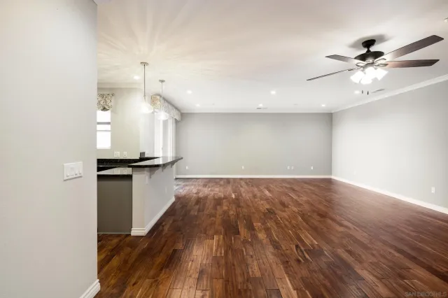 a view of empty room with wooden floor and fan