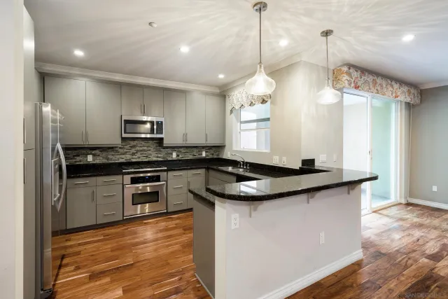 a kitchen with stainless steel appliances granite countertop a sink a stove and a wooden floors