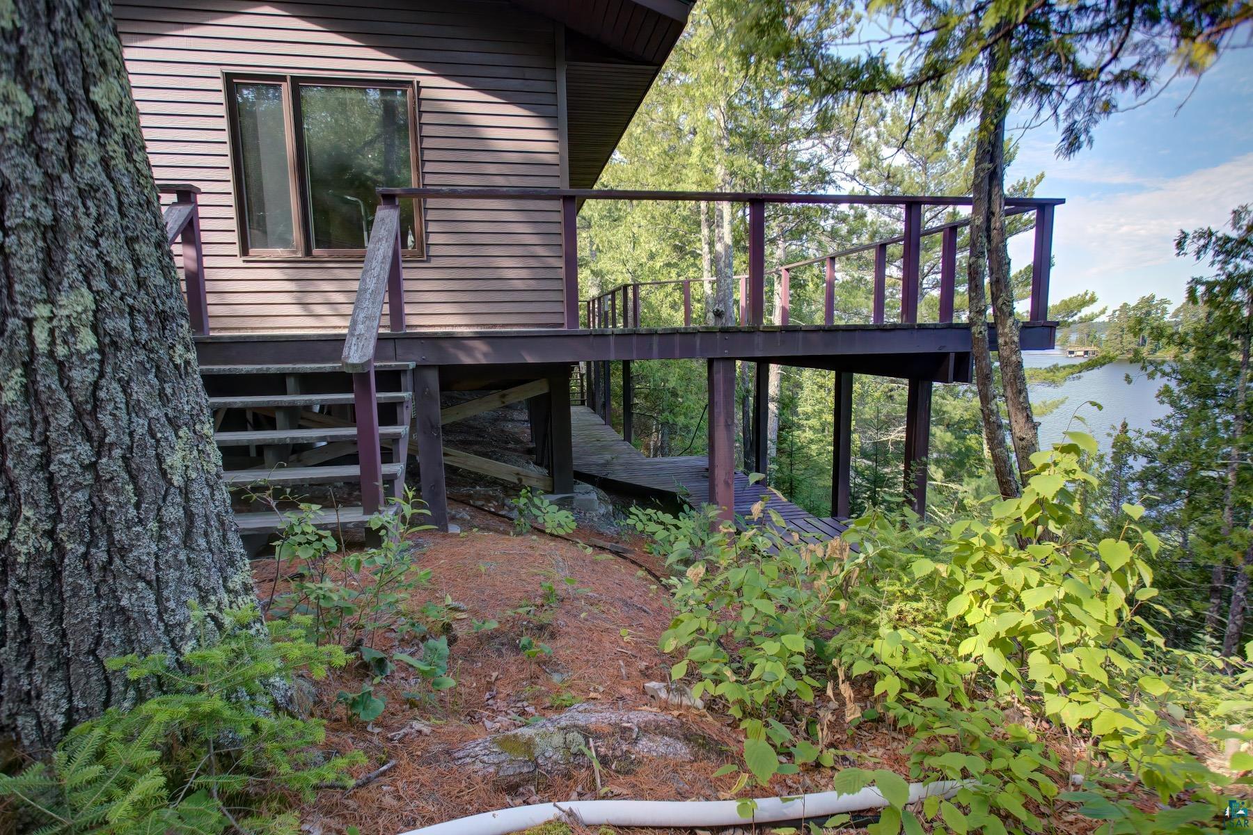 2811 Schaeffer Road Ely, MN 55731 - Photo 6 of 40 Wood-sided exterior featuring a window, an elevated wooden deck with railings, and a stairway with wooden handrails