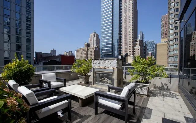 a living room with furniture and a floor to ceiling window and kitchen view
