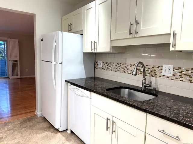 a kitchen with granite countertop a refrigerator sink and cabinets