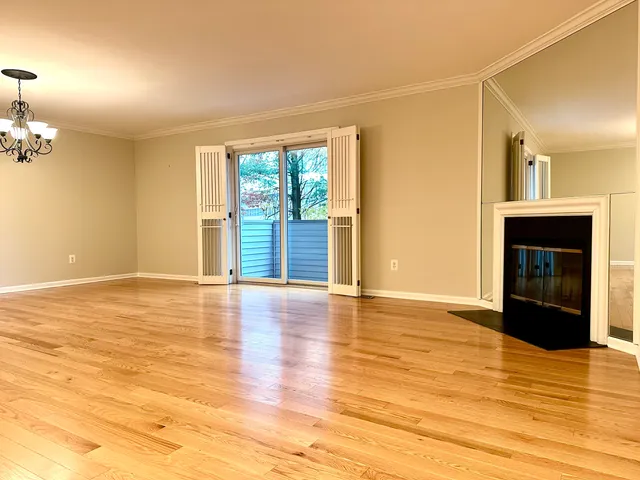 a view of an empty room with window and wooden floor