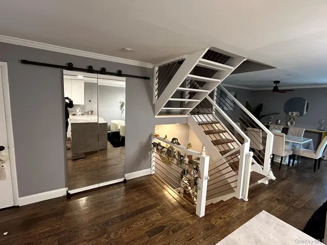 a view of an empty room with wooden floor and stairs