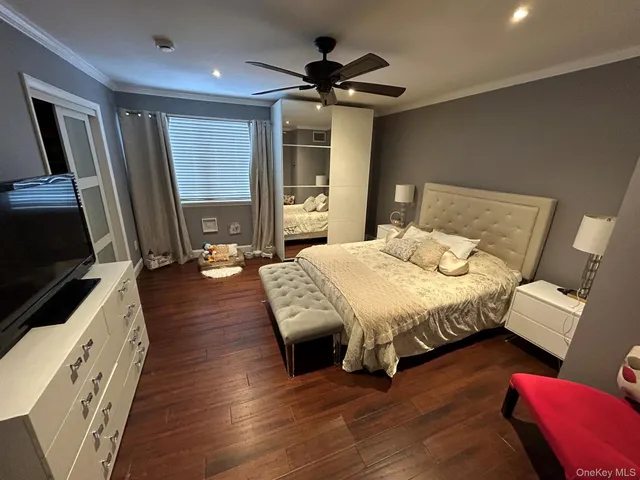 a spacious bedroom with a bed and a flat tv screen on dresser