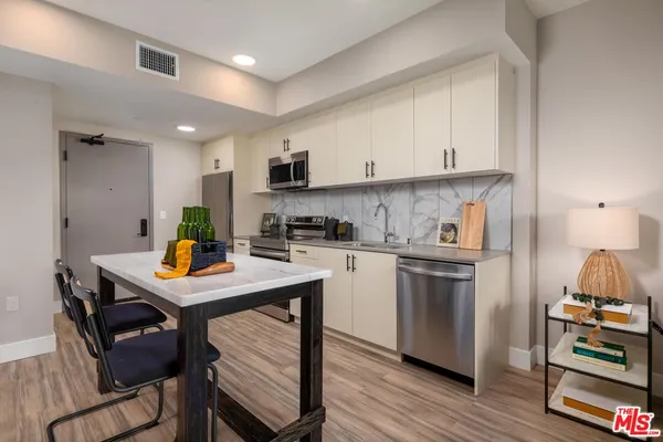 a kitchen with stainless steel appliances a table chairs refrigerator and cabinets