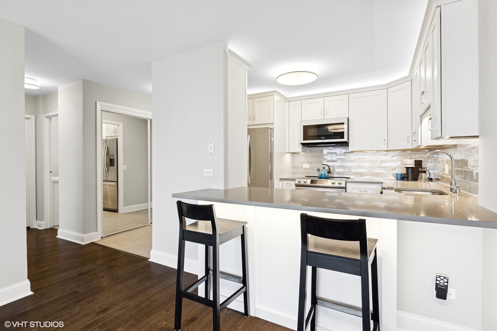 5415 North Sheridan Road, Unit 3004 Chicago, IL 60640 - Photo 5 of 26 a kitchen with stainless steel appliances granite countertop a stove top oven a sink dishwasher and a refrigerator with wooden floor