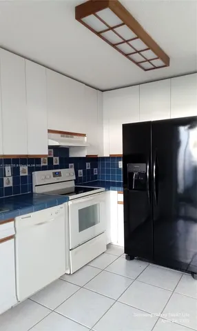 a kitchen with granite countertop a refrigerator and a stove top oven