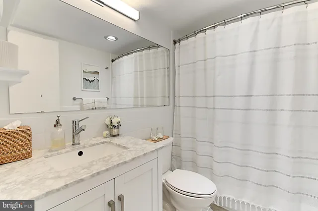 a bathroom with a granite countertop sink a toilet and a mirror