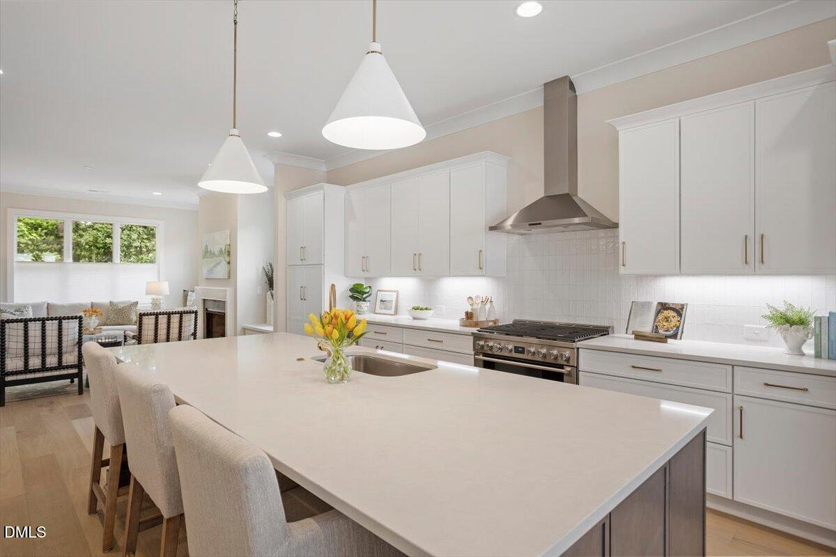 811 Maple Berry Lane, Unit 101 Raleigh, NC 27607 - Photo 11 of 45 a kitchen with a stove a chandelier a dining table and chairs with wooden floor