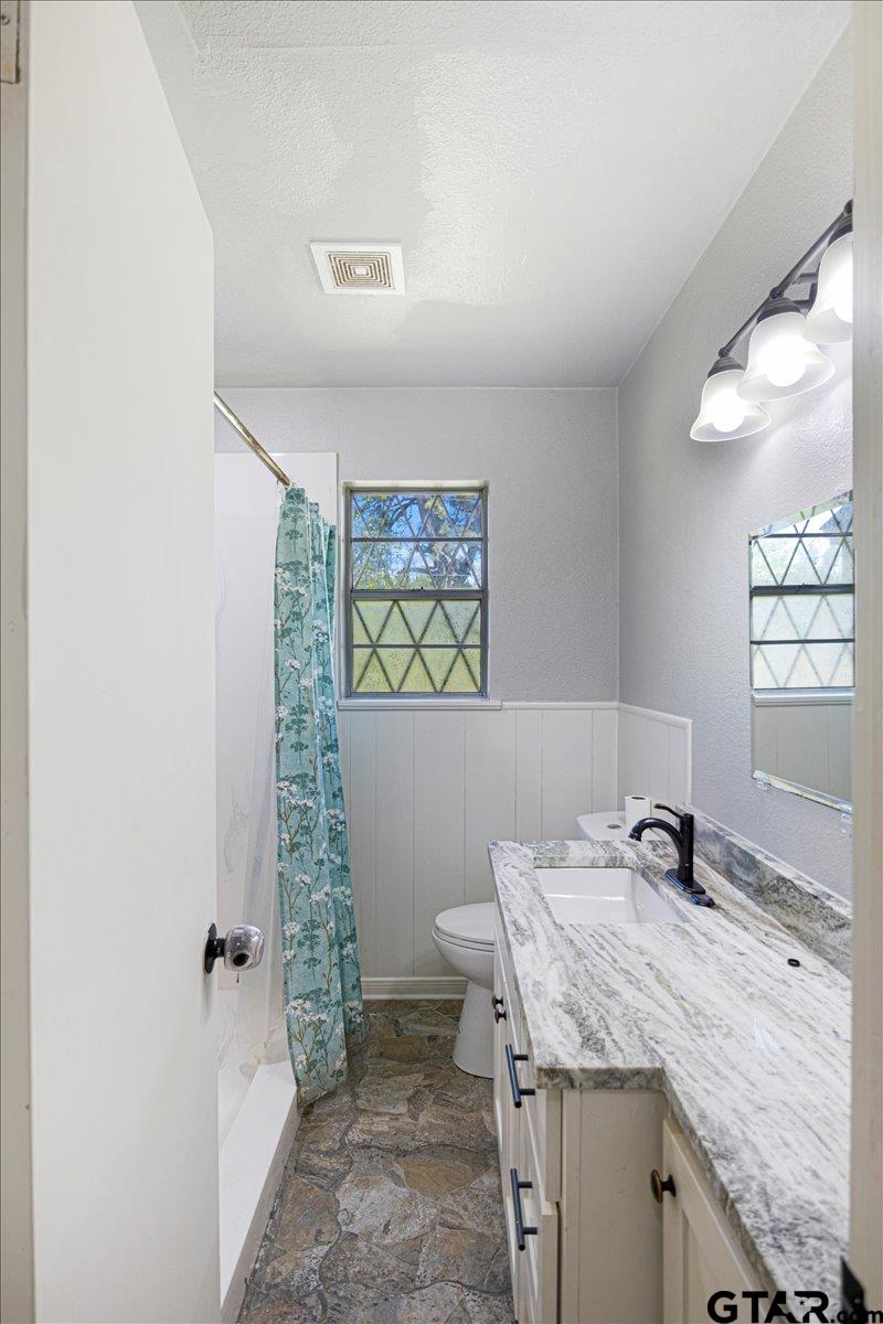 10638 County Road 384 Tyler, TX 75708 - Photo 12 of 33 a bathroom with a granite countertop sink a toilet a mirror and shower