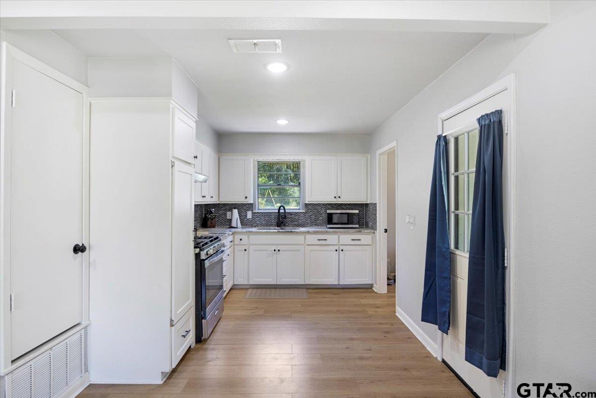 10638 County Road 384 Tyler, TX 75708 - Photo 6 of 33 a kitchen with white cabinets and stainless steel appliances
