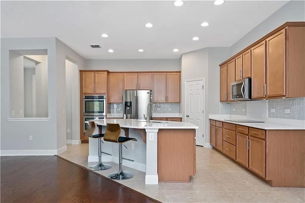 8752 Powder Ridge Trail Windermere, FL 34786 - Photo 11 of 31 a kitchen with stainless steel appliances kitchen island granite countertop a stove a sink and a refrigerator