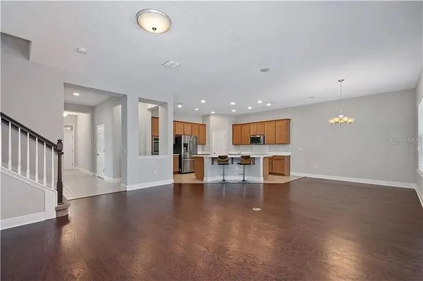 an empty room with wooden floor and a dining room