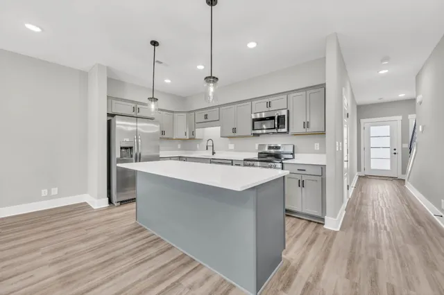 a kitchen with stainless steel appliances kitchen island a refrigerator and a wooden floors
