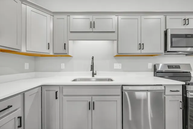 a kitchen with white cabinets sink and stainless steel appliances