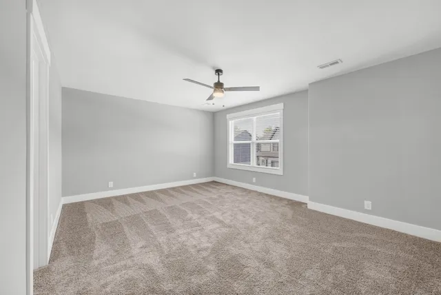an empty room with windows and ceiling fan