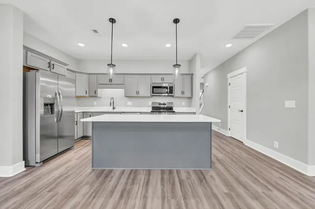 a kitchen with stainless steel appliances granite countertop a refrigerator a oven a sink dishwasher and white cabinets with wooden floor