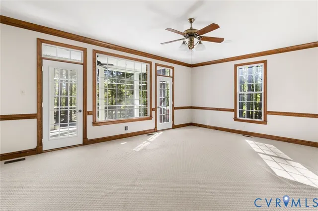 an empty room with ceiling fan and windows