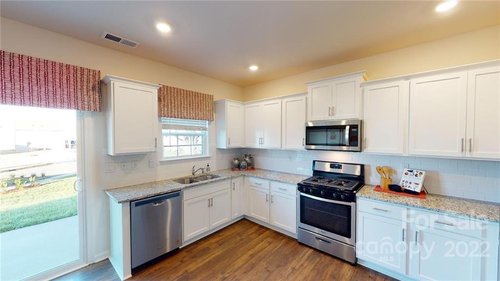 7588 Stonehouse Drive Gastonia, NC 28056 - Photo 7 of 20 a kitchen with granite countertop white cabinets appliances a sink and a window