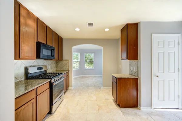 a large kitchen with stainless steel appliances granite countertop a stove a sink and a microwave