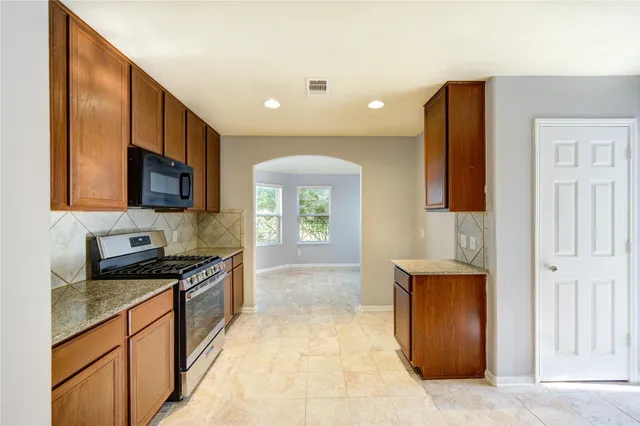 a large kitchen with stainless steel appliances granite countertop a stove a sink and a microwave