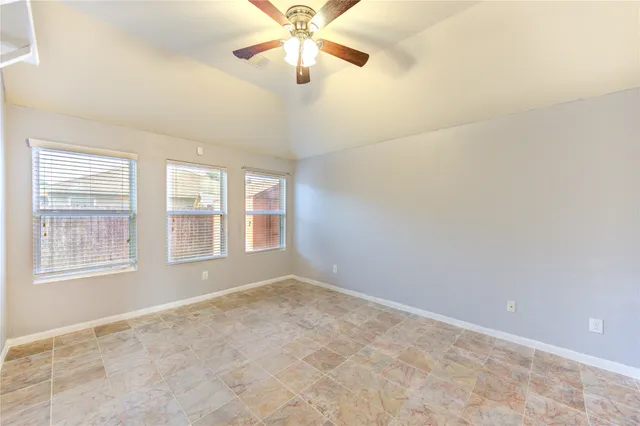 an empty room with chandelier fan and windows