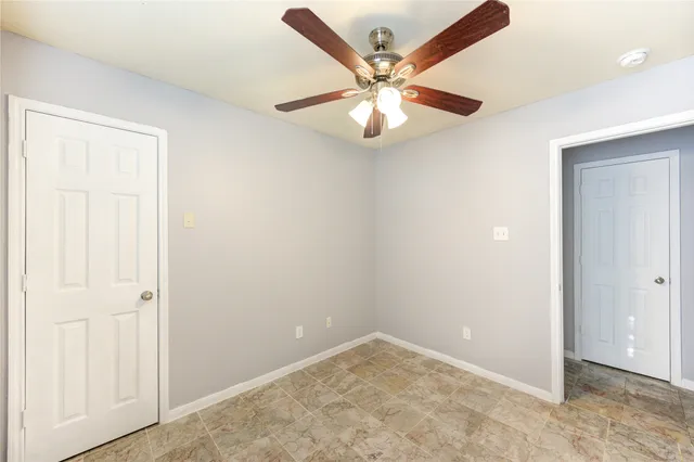an empty room with a chandelier fan and closet area