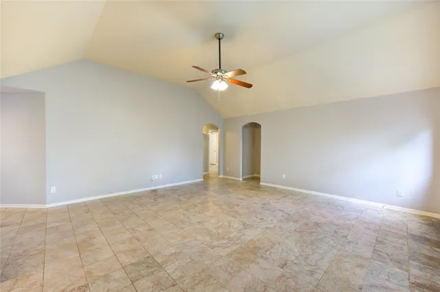 a view of an empty room with chandelier fan