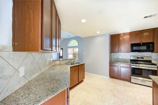 a kitchen with stainless steel appliances granite countertop a stove a sink and a microwave