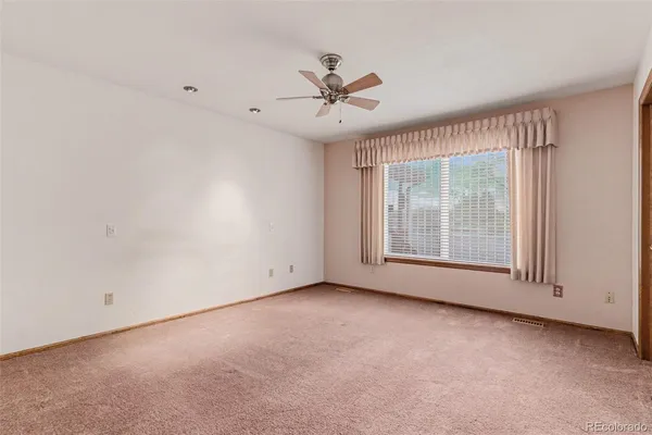 an empty room with chandelier fan and windows