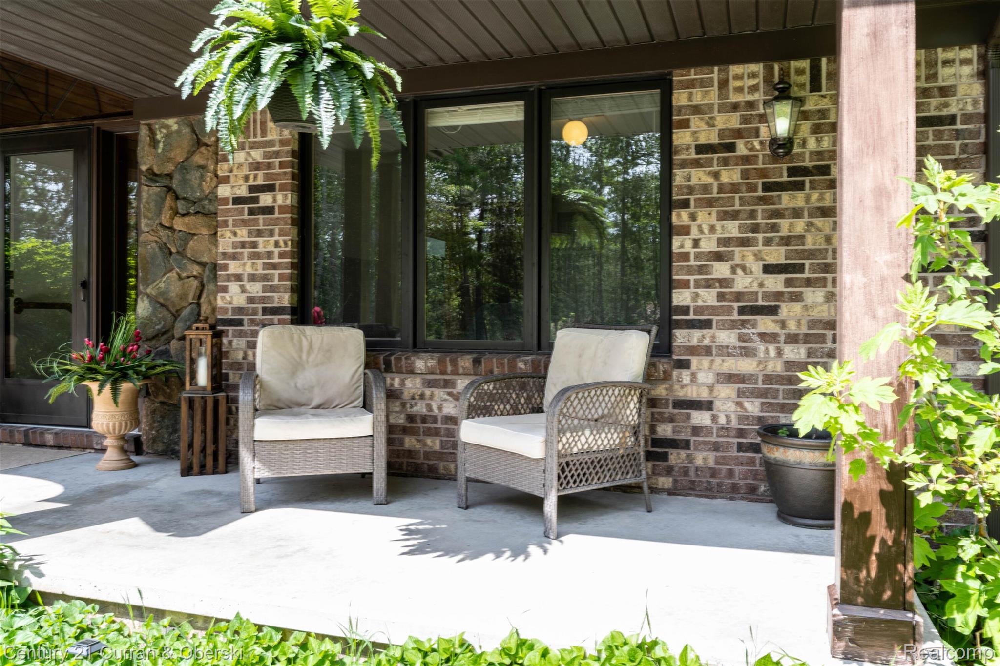 8775 Winding Rdg Drive Millersburg, MI 49759 - Photo 8 of 53 Inviting covered porch featuring mixed brick and stone facade, large windows, and an exterior wall lantern