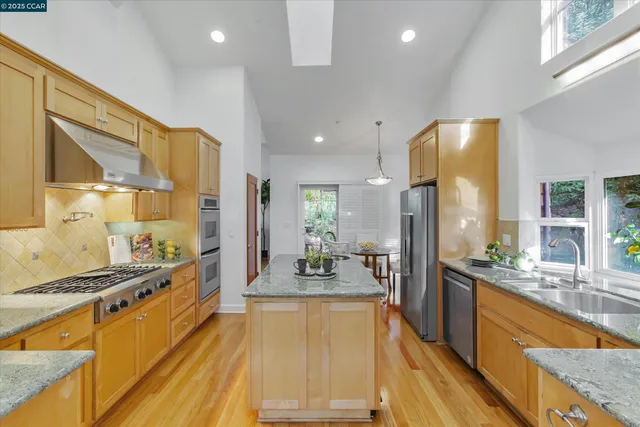 a kitchen with stainless steel appliances granite countertop a sink a stove and a microwave oven with wooden floor