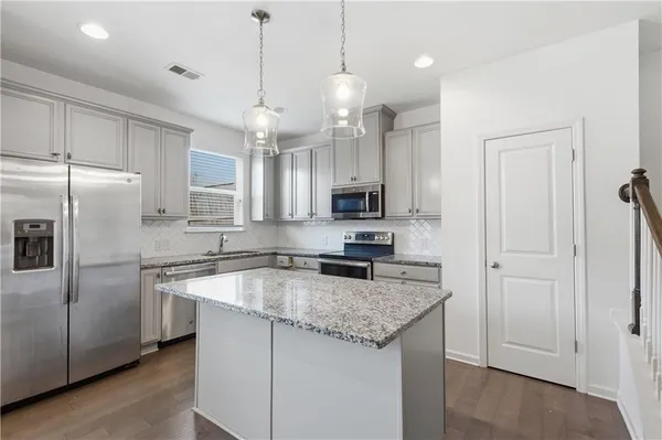 a kitchen with granite countertop a center island a sink stainless steel appliances and cabinets
