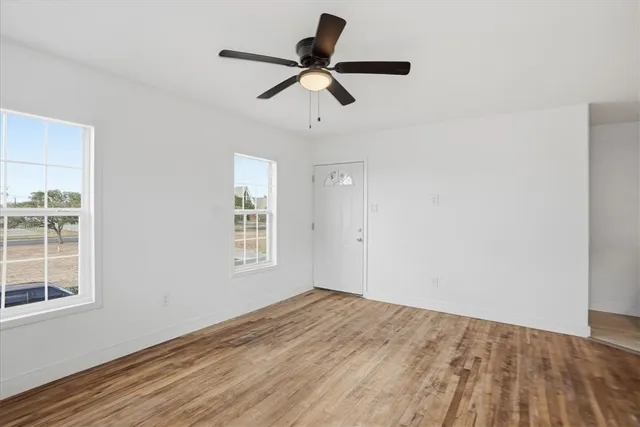 a view of empty room with wooden floor and fan