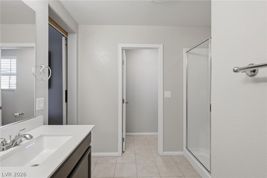 1921 Miller Ridge Avenue North Las Vegas, NV 89031 - Photo 20 of 26 This bright bathroom features a single vanity, a walk-in shower, and tile flooring for a pristine look.