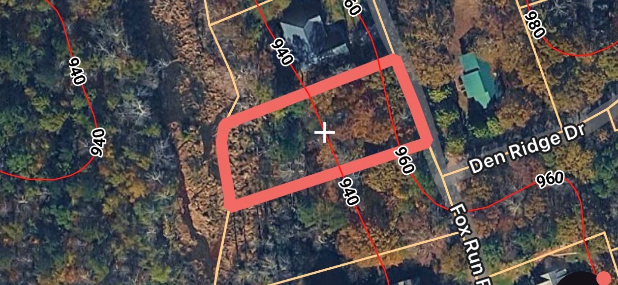 This aerial view showcases a residential lot nestled within a serene, wooded landscape.