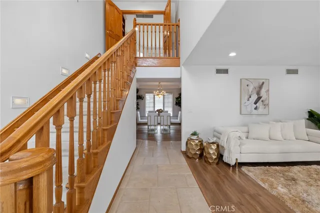 a living room with couches a chandelier and a dining table with garden view